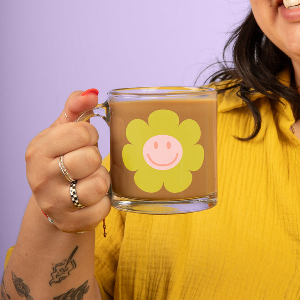 Girl holding a green smiley flower mug.