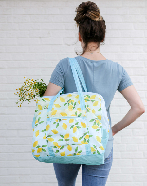 a girl holding a ripstop bag with blue straps and yellow lemons and flowers