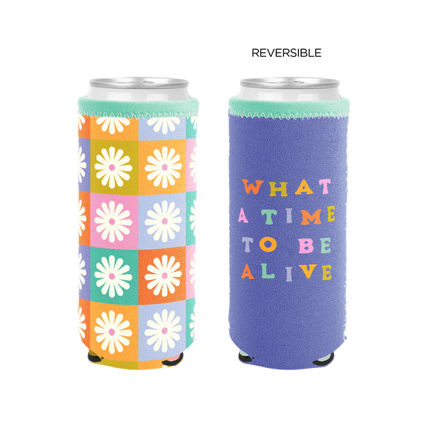 Reversible slim can cooler; one side with multi-color checker and white daisies design, one side blue with multi-color text that reads "WHAT A TIME TO BE ALIVE"