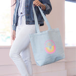 Girl in a denim jacket holding a cute canvas tote bag in light denim with daydreamers club design.