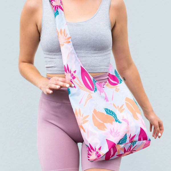 girl wearing a pale blue colored bagabond crossbody tote with cranberry, orange, teal and pink fall floral leaves