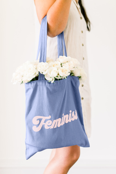 Cute canvas tote bag hanging on a woman's elbow with white roses inside.