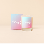 Candle rocks glass with bright blue-to-pink ombre decal and text that reads "Virgo" with minimalist, white sparkle stars surrounding the text; "the busy-body perfectionist" sits at the bottom of the decal. Box packaging with the same design sits behind glass.