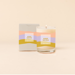 Rocks candle reading "KEEP GOING" in front of tri-color horizontal stripes around candle. Box packaging with same design and text as candle. 