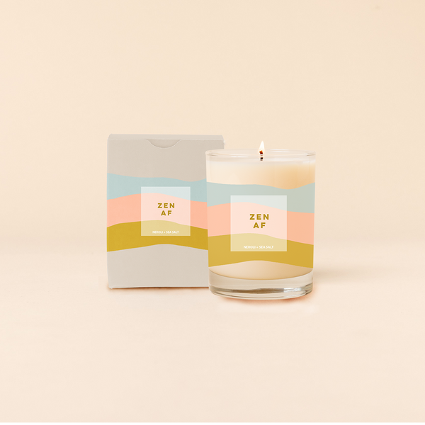 Rocks candle reading "ZEN AF" in front of tri-color horizontal stripes around candle. Box packaging with same design and text as candle.