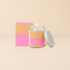 An 8 oz. candle w/ a lid and a split-colored decal (Orange and Pink) and the phrase 