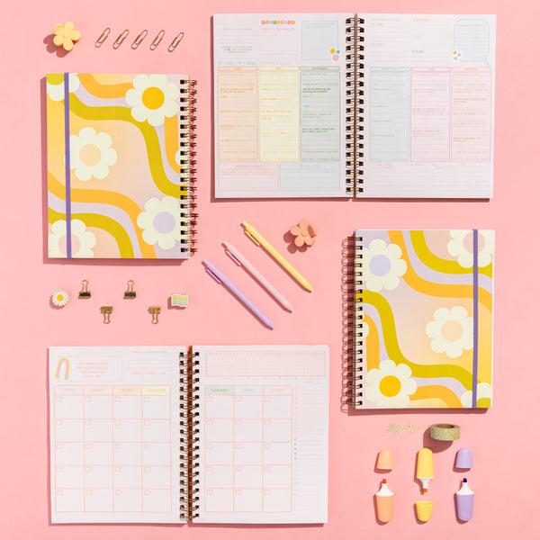 Wavy Daisy planner open an closed. Opened on full monthly calendar page, and monthly dashboard while jotter pens, mini highlighters, wash-tape, daisy enamel pen, and flower claw clips.