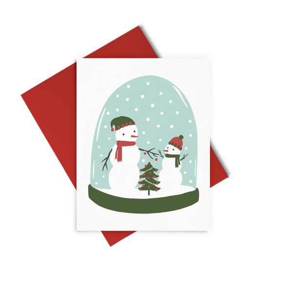 a greeting card with two snow men in a snow glob holding hands with a christmas tree between them.