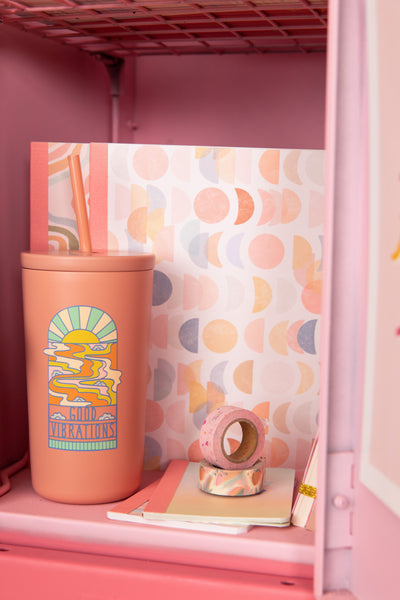 Cold cup/tumbler with peach & blue "good vibrations" design in a pink school locker.