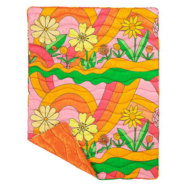 puffy quilted blanket with big colorful flowers and rainbow swirls with a solid color on the backside