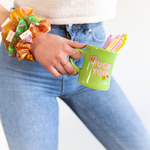 girl holding old school green diner mug in hand with saying "fuck you" with flowers, pens in the cup, three floral print scrunchies on her wrist