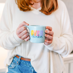 Girl in a cozy sweater holding a cute light blue element mug with colorful "over thinker" on it.