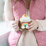 a girl holding a cute glass mug with a rainbow that says fuck mornings
