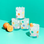 Rock glass set- daisy along with a sliced orange and teal background.