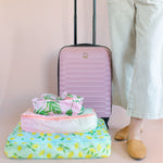Garden party packing cubes stacked largest to smallest with woman holding a pink suitcase.