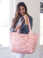 Brunette girl holding a cute tote bag in pink canvas with navy pixie sticks and double shoulder strap.