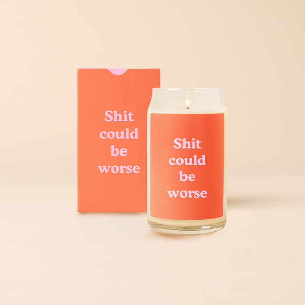 16 oz candle can glass with red decal and text that reads "Shit could be worse" in pink font. Red box with same design sits behind candle.