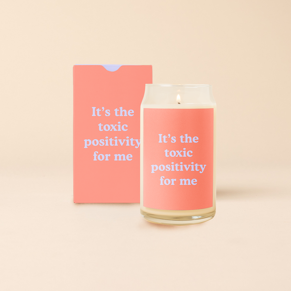 16 oz candle can glass with coral decal and text that reads "It's the toxic positivity for me" in lavender font. Coral box with same design sits behind candle.