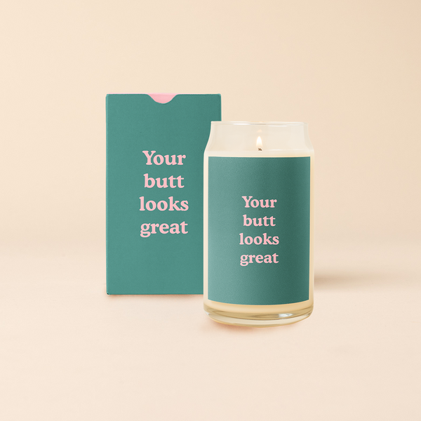 16 oz candle can glass with green decal and text that reads "Your butt looks great" in pink font. Green box with same design sits behind candle.