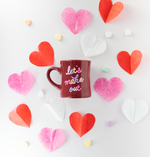 Let's make out sangria diner mug surrounded by paper hearts in red, white, and pink. Also surrounded with candy conversation hearts.