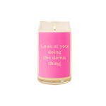 A 16 oz. candle with a pink decal on it with the phrase "Look at you doing the damn thing" printed on.