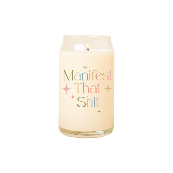 A 16 oz. candle with "Manifest that shit" printed on in multicolored lettering. Twinkle stars are surrounding the phrase.