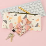 A small pencil pouch sits next to a keyboard with a small reversible pouch and pair of keys next to it.