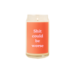 A 16 oz. candle with a red decal on it with the phrase "Shit could be worse" printed on.