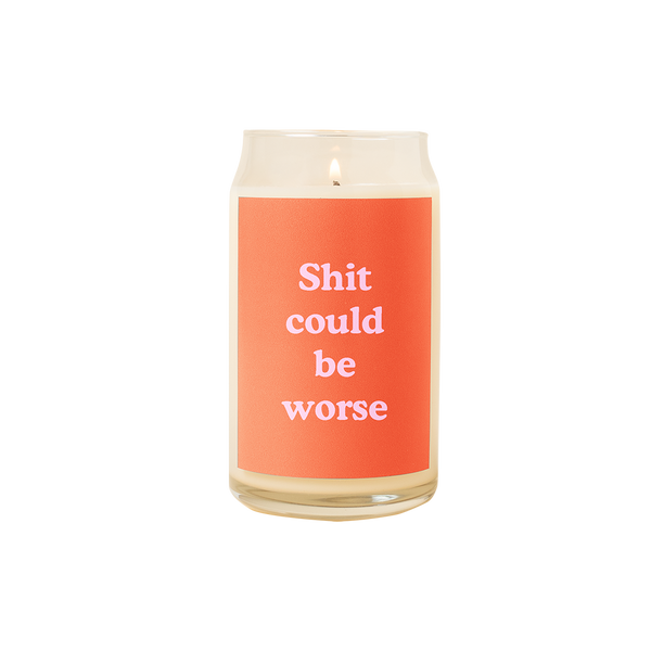 A 16 oz. candle with a red decal on it with the phrase "Shit could be worse" printed on.