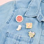 Our cute enamel pins pinned to a chambray denim shirt. Wild child, fuck this shit, so many feelings, and our confetti hand are the pins used in this picture.