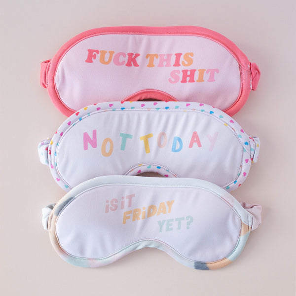A light pink "Fuck This Shit" eye mask with multi colored lettering, a white "Not Today" eye mask with multicolored lettering and a mini hearts perimeter, and a "Is it Friday yet?" eye mask with a multicolored pastel lining.