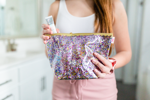 Lady placing makeup in her sparkly confetti tweedle dum pouch.