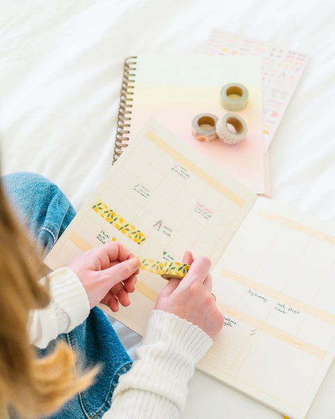 Girl placing washy tape inside her weekdays planner.