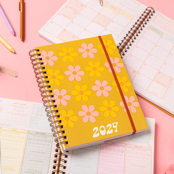 Day to Daisy 2024 Dated Goal Getter Planner laying on an open planner with jotter pens.