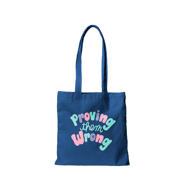 Navy canvas tote bag that says Proving Them Wrong in colorful lettering.