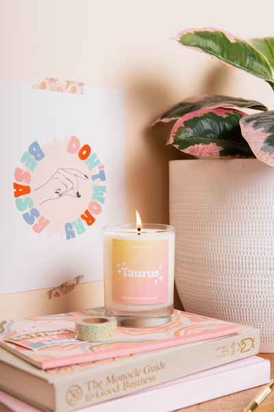 Taurus Astrology Rocks Glass Candle with a Orange and Coral gradient background.