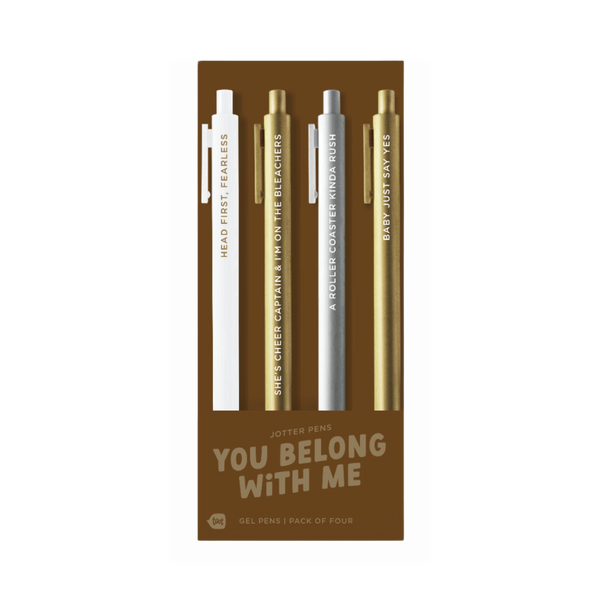A pack of four gel jotter pens displayed on bronze packaging labeled “YOU BELONG WITH ME.” Each pen features a metallic or neutral tone with Taylor Swift-inspired lyrics:
