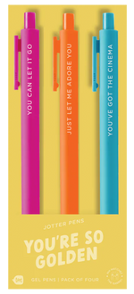 A set of three colorful jotter pens on yellow packaging labeled “YOU’RE SO GOLDEN.” The pink pen says “YOU CAN LET IT GO,” the orange pen reads “JUST LET ME ADORE YOU,” and the blue pen says “YOU’VE GOT THE CINEMA.” The packaging notes this is a pack of four gel pens, though one pen is not shown.