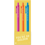A set of three colorful jotter pens on yellow packaging labeled “YOU’RE SO GOLDEN.” The pink pen says “YOU CAN LET IT GO,” the orange pen reads “JUST LET ME ADORE YOU,” and the blue pen says “YOU’VE GOT THE CINEMA.” The packaging notes this is a pack of four gel pens, though one pen is not shown.