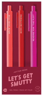 A set of three bold-colored jotter pens on deep red packaging labeled “LET’S GET SMUTTY.” The coral pen says “SPICE LEVEL: FIVE,” the red pen reads “BOOK BOYFRIEND,” and the magenta pen says “READING FOR ‘THE PLOT’.” Packaging notes it’s a gel pen pack of four, although only three pens are visible, and ink matches the barrel color.