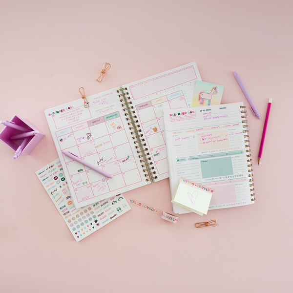 Jotter pens and pencil displayed on two different planners and a sticker sheet. Desk organizer is on the left side with more Lilac Jotter pens in the organizer.