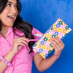 Woman holding a colorful floral-patterned pouch against a blue background