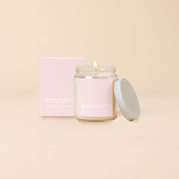 Deep breathes in" soy candle in a clear glass jar with minimalist light pink label and lid, featuring bold, humorous text and matching gift box – scented with notes of sweet citrus and berries.