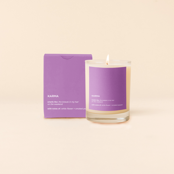 A lit 14oz rocks glass candle with the word "Karma" written on it. There is a matching box in the purple color with the same word "Karma" on it. The candle is all natural soy-based wax (paraffin-free)!! 