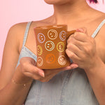 Girl holding brown smiley diner mug with a pink background