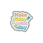 This sticker features a wavy, cloud-like shape. There is a silver glitter boarder and the background is a light blue shade. The phrase "Make today a great day" is written in a different color--orange, mustard, pink, and dark teal. There are starburst icons scattered around the text.