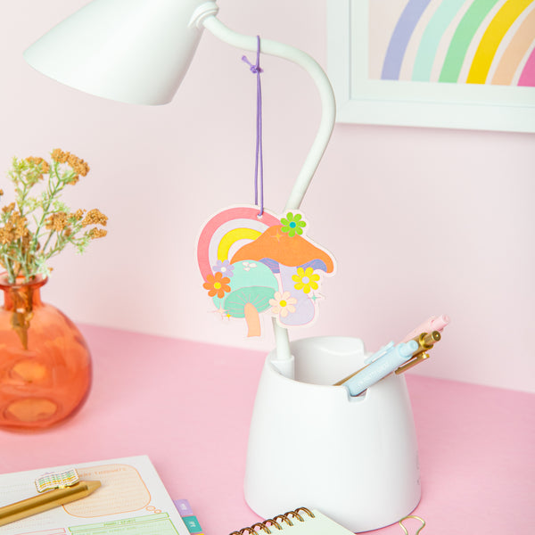 Air freshener of a mushroom with a rainbow and flowers hanging off of a lamp. It has orange, purple, blue, yellow, and pastel colors.