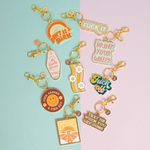All the gold key charm styles laying on a blue and pink background