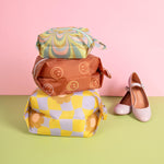 Pink background and the feeling funky packing pouches along with flats on a green surface.