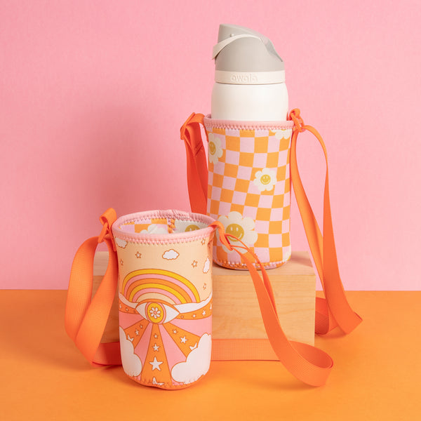 Orange and pink reversible simple hydration slings on an orange surface and pink background
